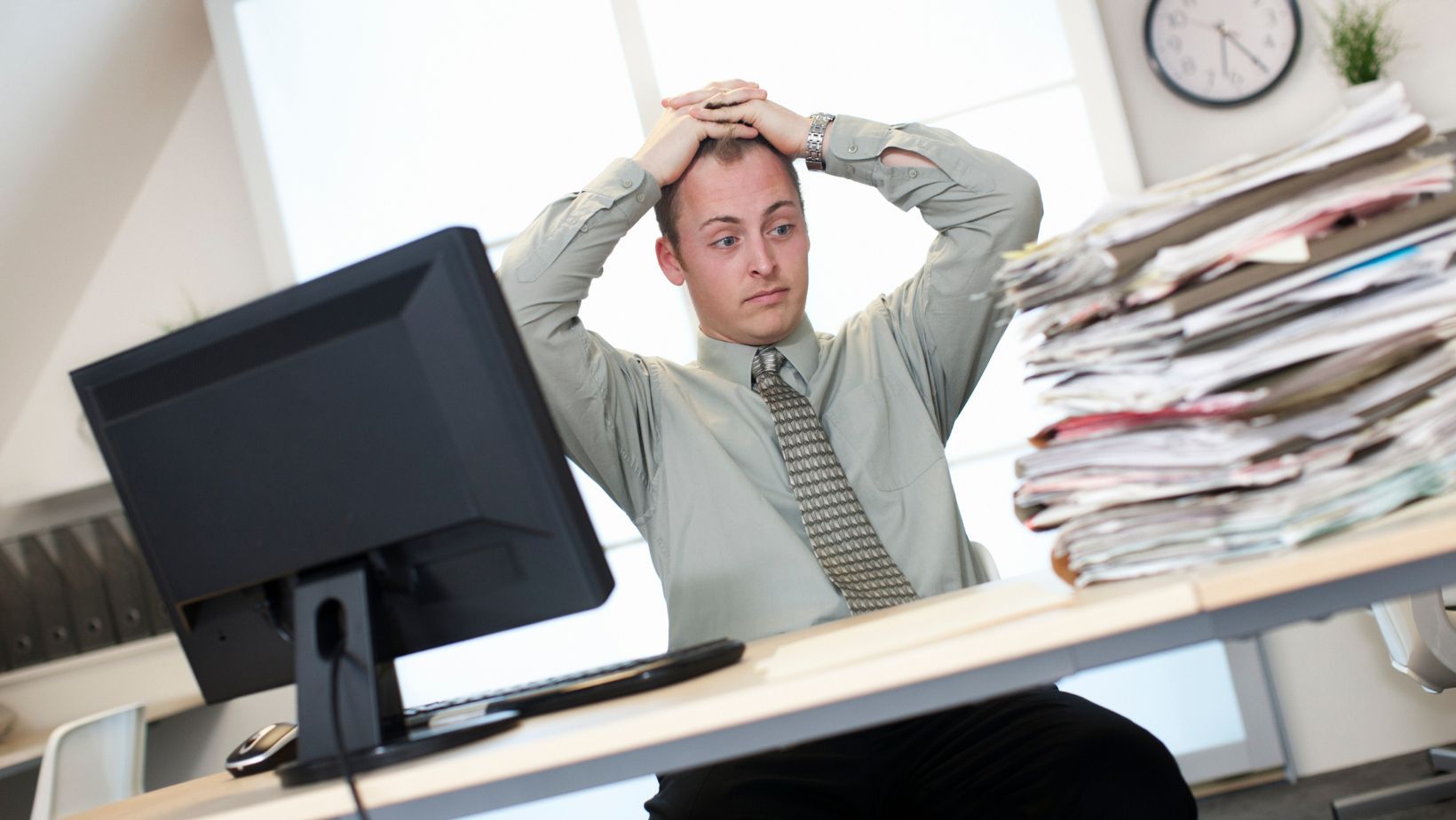 Office worker stressed while looking at pile of documents